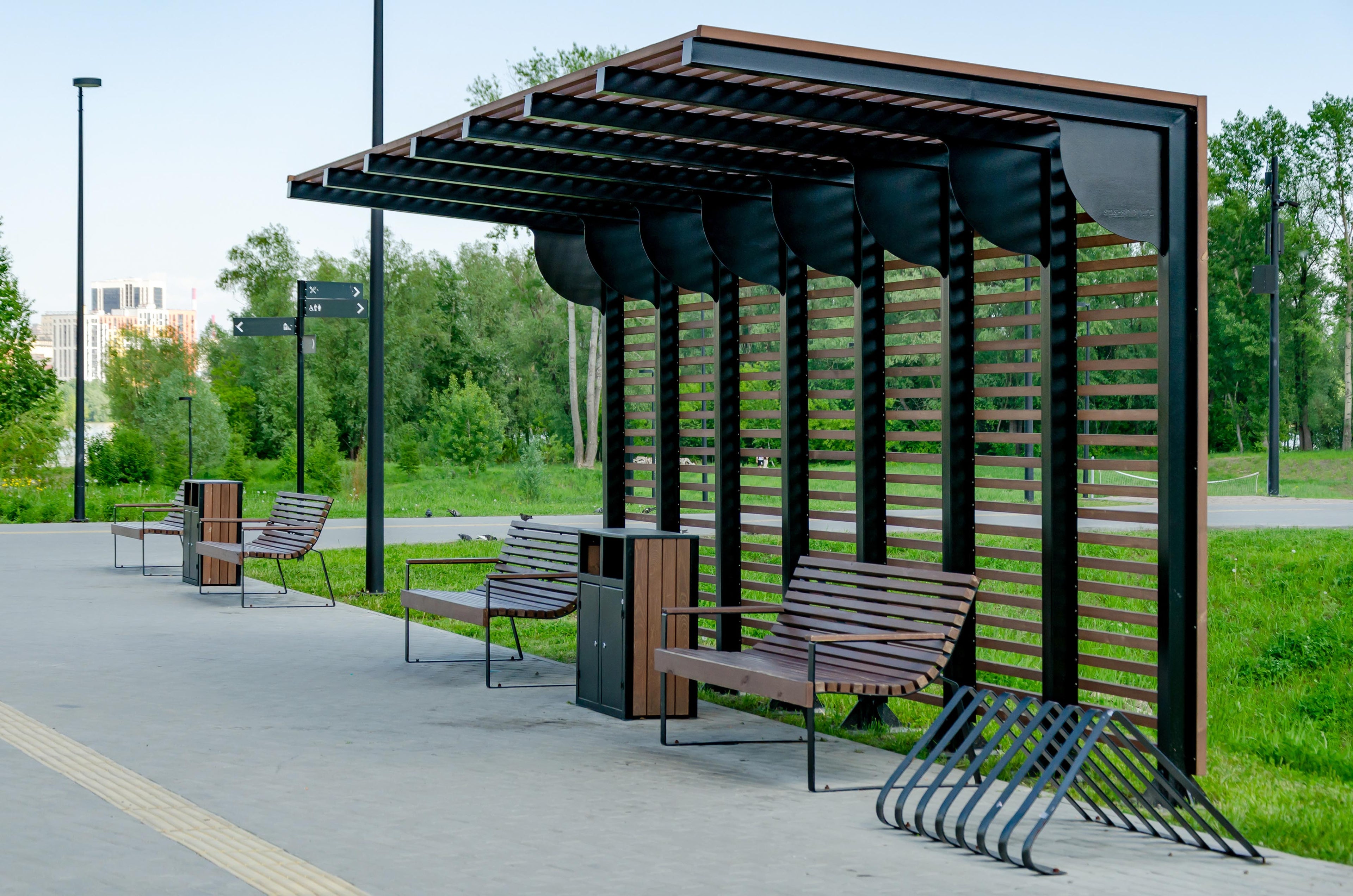 Bushaltestelle aus schwarzem Metall mit Holz, Bänken und Fahrradständer